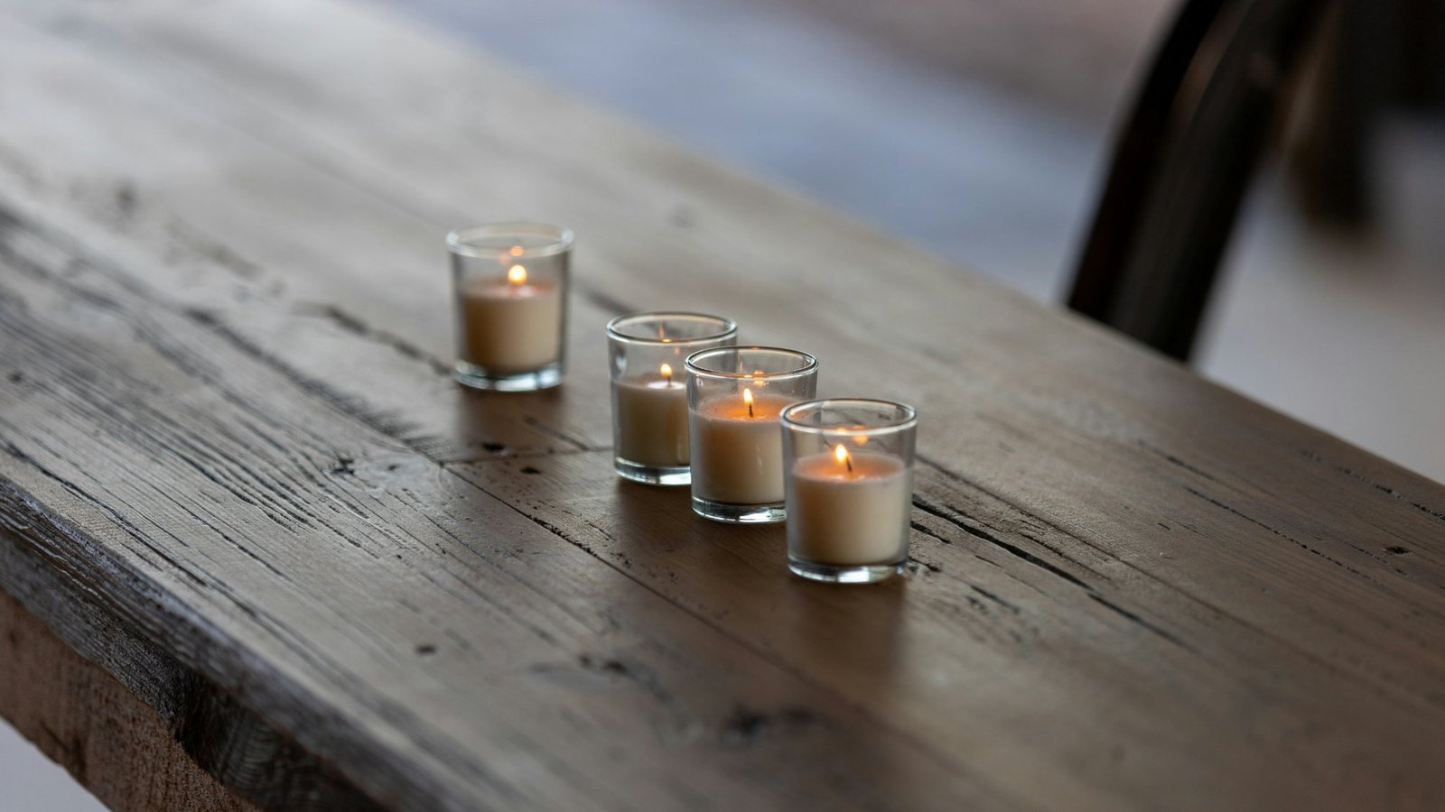 Cuatro velas encendidas sobre un banco de madera, luz cálida al atardecer