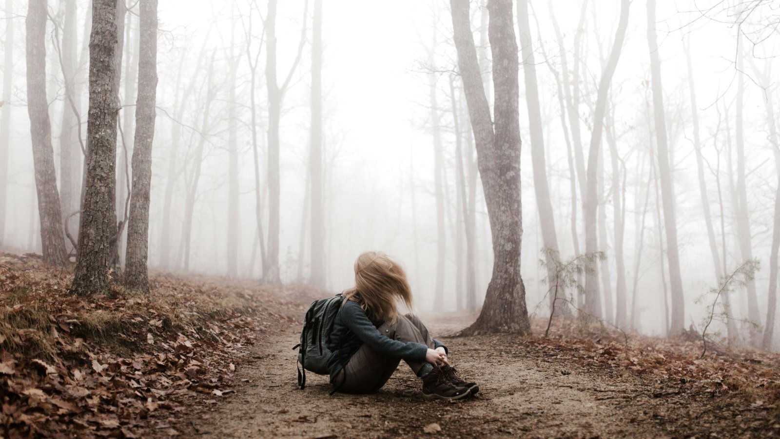 Mujer sentada en un camino de bosque brumoso